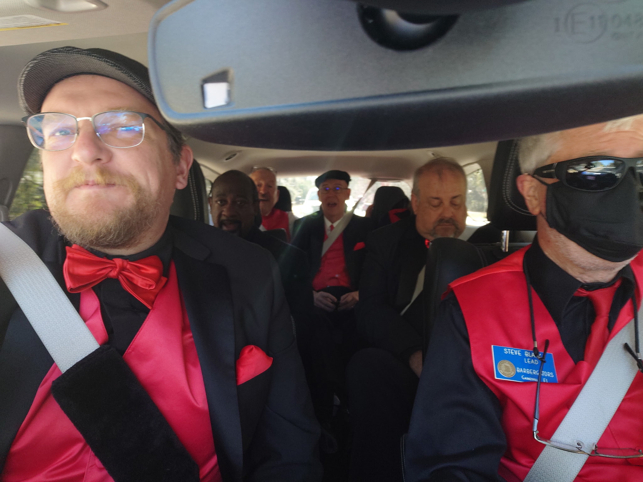 Members of the chorus in their red ties and vests traveling together in a van to their next gig.