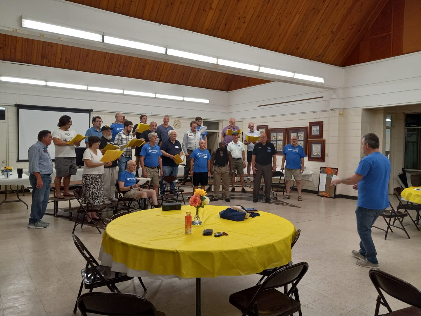 Chorus with guests rehearsing on the risers at Audition Night. Guests are holding yellow guest folders